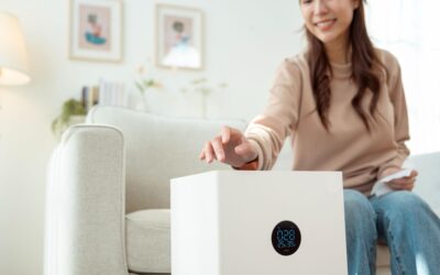 A woman turning on an air purification system in the living room of her home.