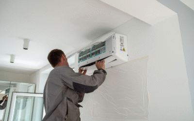 An HVAC technician mounts an air conditioning unit on an apartment wall.
