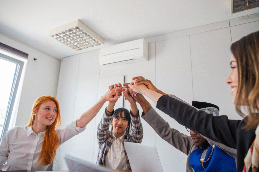 A business team unites with raised hands in a comfortable office environment maintained by a ductless mini split.
