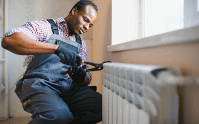 A technician administers heating services to a home radiator.