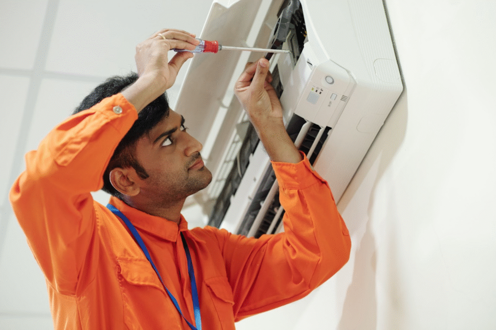 A  HVAC technician in orange coveralls sets up a mini split during AC installation.