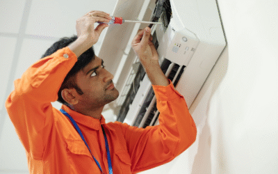 A  HVAC technician in orange coveralls sets up a mini split during AC installation.