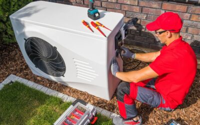 A technician repairs a heat pump unit sitting in a home’s backyard.